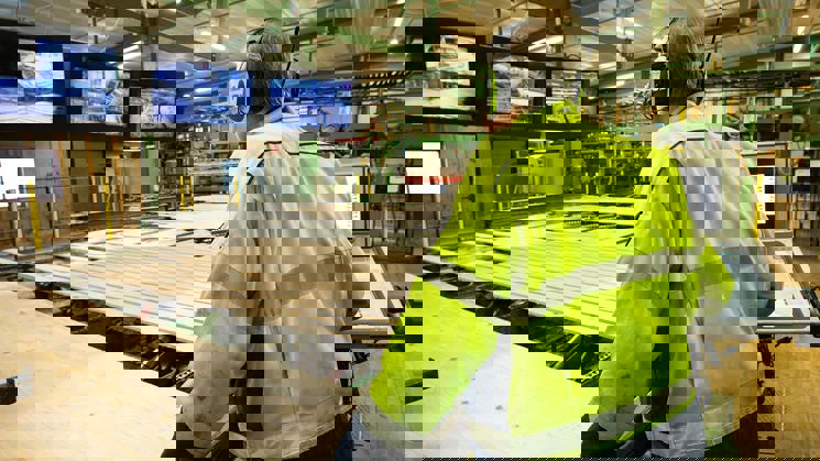 man kontrollerar träprodukter i sågverk